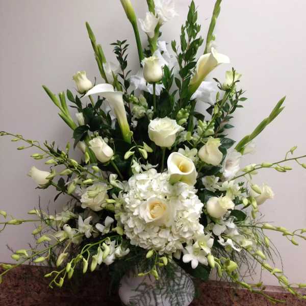 White floral arrangement with calla lilies, roses, and hydrangeas in a vase
