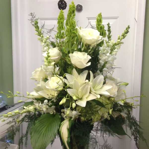 White lilies and roses in a tall glass vase