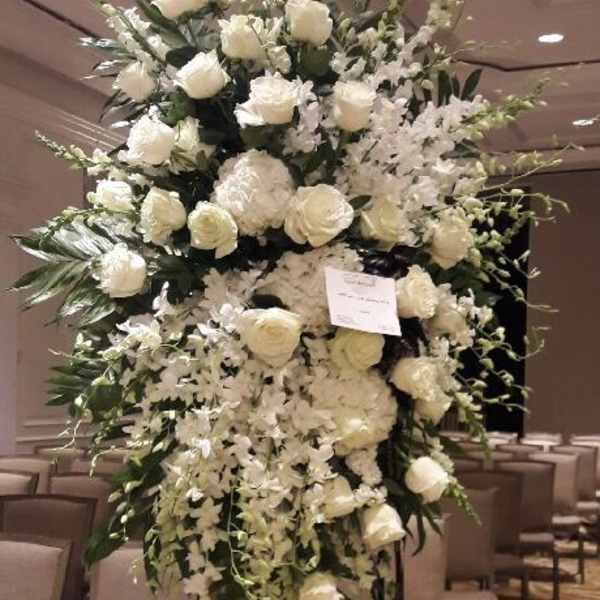 Tall white floral arrangement with roses and orchids on a stand