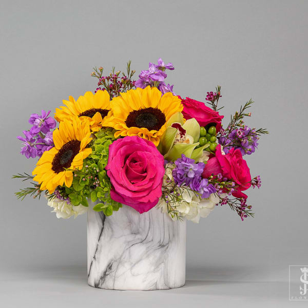 Bright mixed bouquet in a marble-pattern vase with sunflowers and pink roses