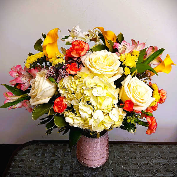 Mixed bouquet of roses, hydrangea, calla lilies, and alstroemeria in a pink vase