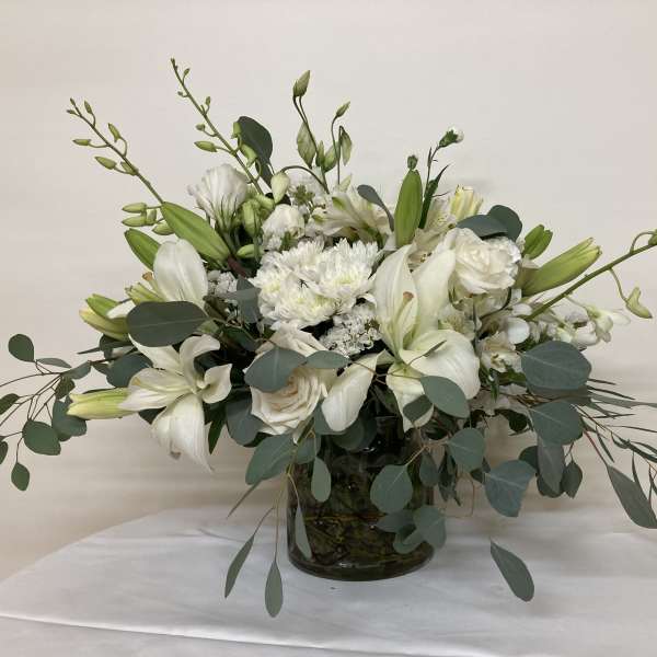 White floral arrangement in a glass vase with long green stems