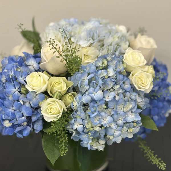 Blue hydrangeas and cream roses in a glass vase