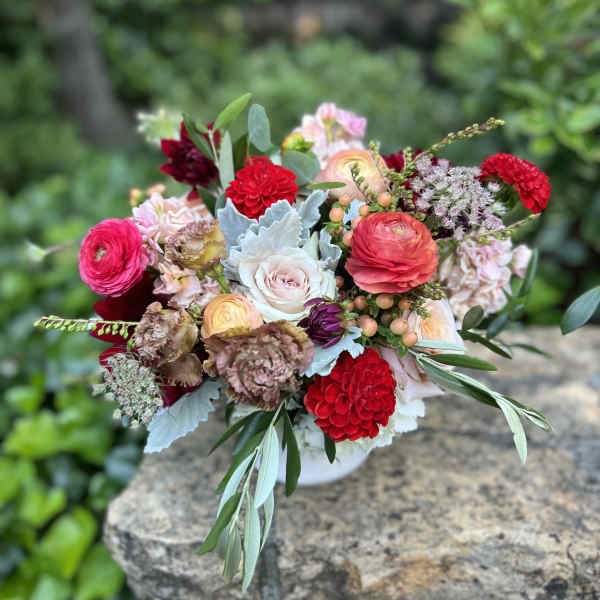 Mixed bouquet of pink, red, and white flowers in a low vase
