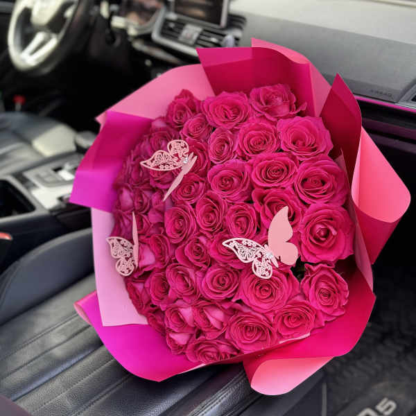 Bouquet of hot pink roses wrapped in pink paper with butterfly decorations