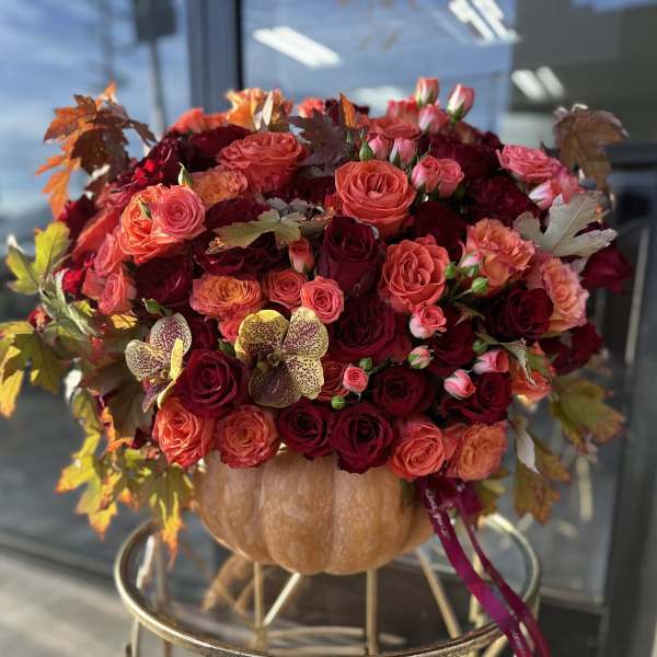 Large bouquet of red and coral roses in a pumpkin vase