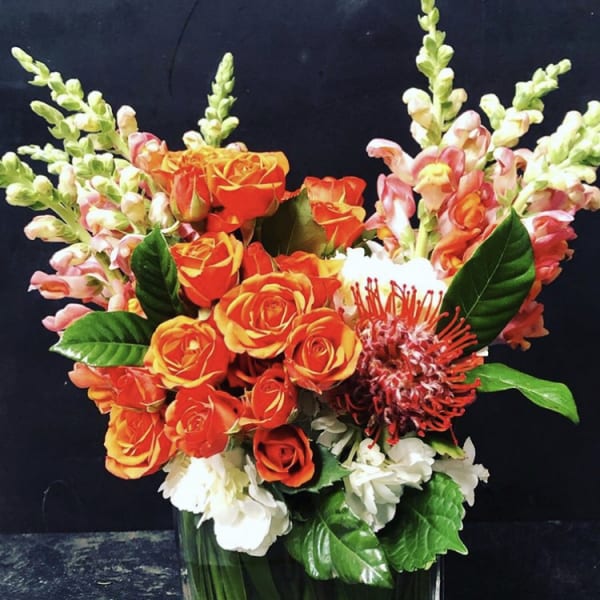 Orange roses with pink snapdragons in a glass vase