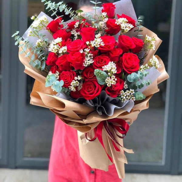 Bouquet of red roses with white filler flowers and eucalyptus in brown paper