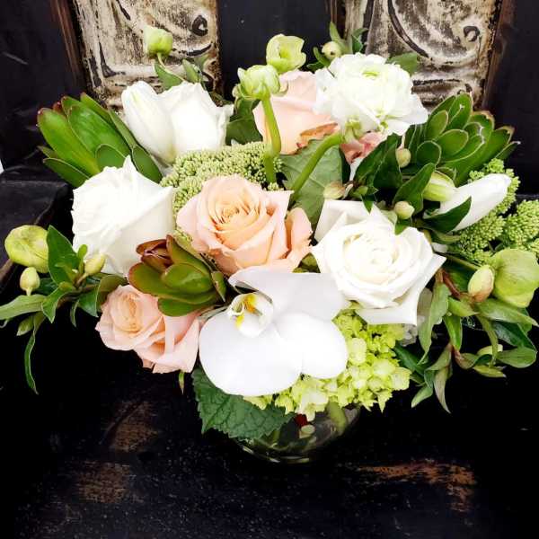 Bouquet of white and peach roses with white orchids in a glass vase