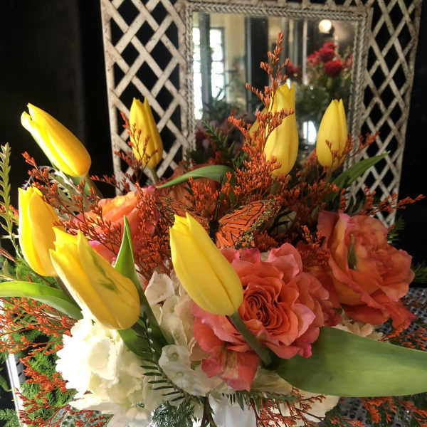Bouquet of yellow tulips and orange roses in a white vase