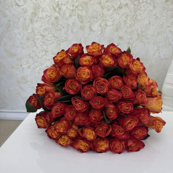 Large bouquet of red and orange roses on a white surface