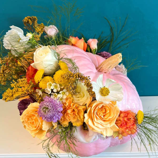 Floral arrangement in a pink pumpkin vase with roses and mixed blooms