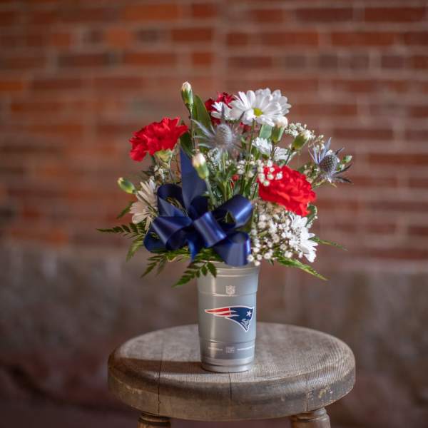 Bouquet of red and white flowers in a silver cup with a blue ribbon