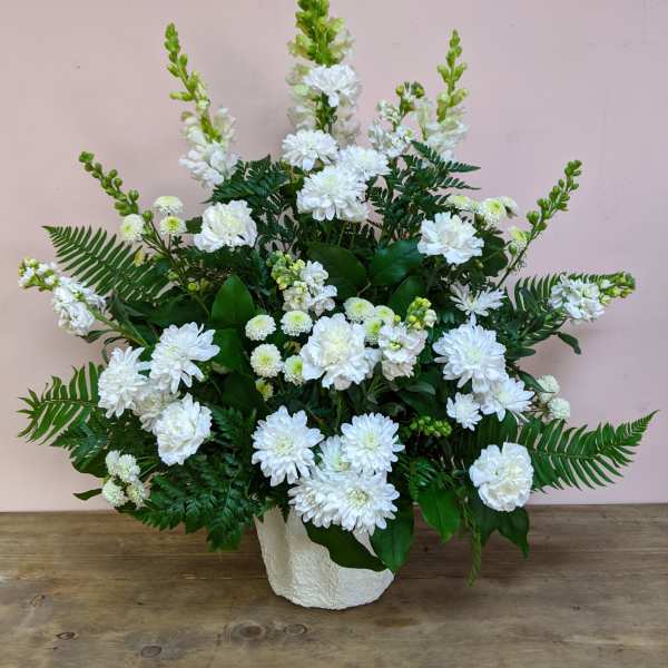 White floral arrangement in a textured white vase with fern accents