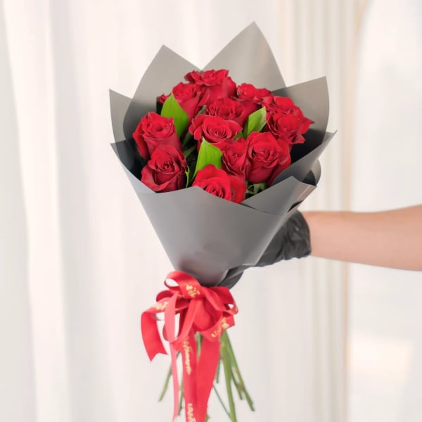 Bouquet of red roses wrapped in black paper with a red ribbon
