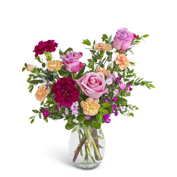 Mixed bouquet of pink roses and red and peach carnations in a clear glass vase