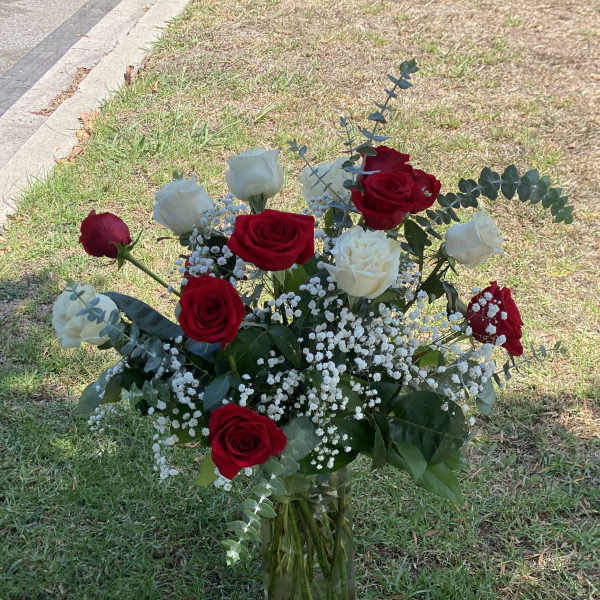 Red and white roses in a clear glass vase with baby's breath