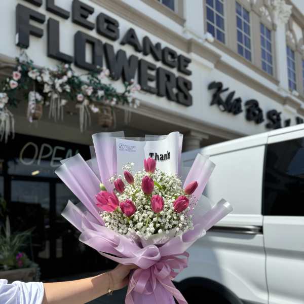 Pink tulip bouquet wrapped in lavender paper with baby's breath