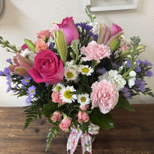 Pink and purple mixed bouquet with roses, lilies, carnations, and daisies