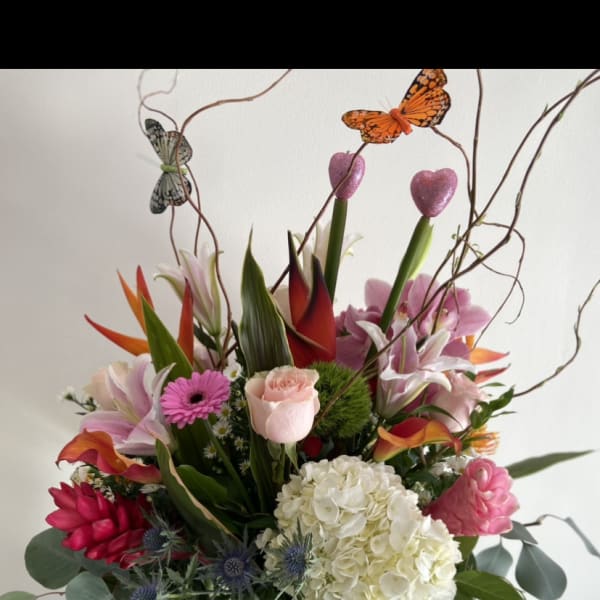 Mixed tropical bouquet in a glass vase with butterfly picks