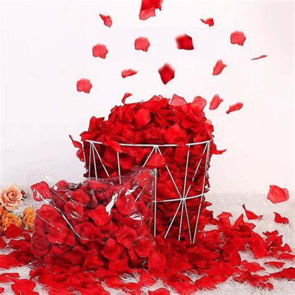 Red rose petals spilling from a wire basket onto a white surface