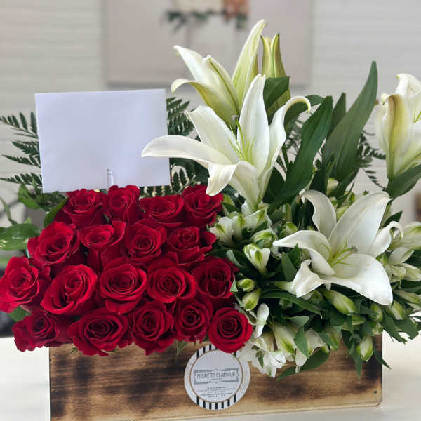 Red roses and white lilies arranged in a wooden box with a blank card