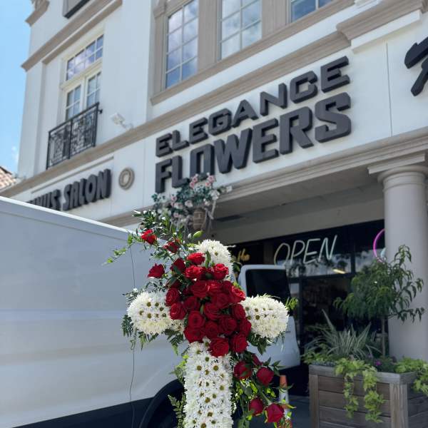 Standing floral cross of red roses and white daisies on an easel