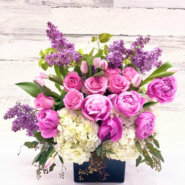 Pink roses and peonies with purple lilacs in a dark vase