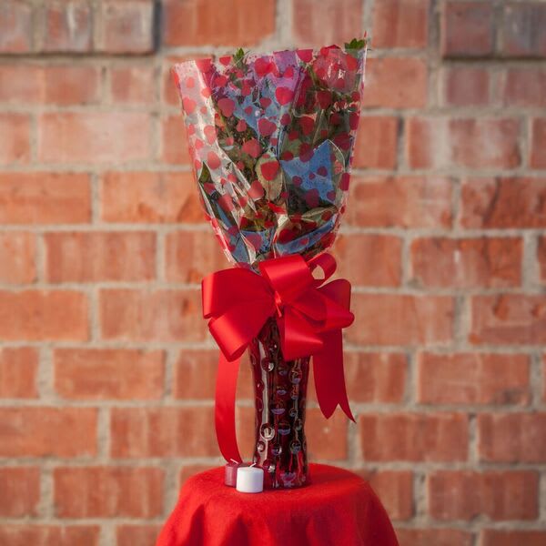 Wrapped bouquet with a red ribbon in a glass vase