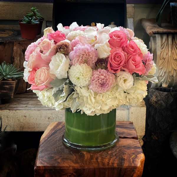 Pink and white flower arrangement in a green glass vase