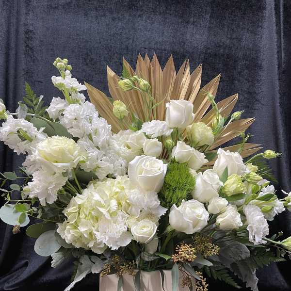 White roses and hydrangeas in a blush vase with gold fan accents