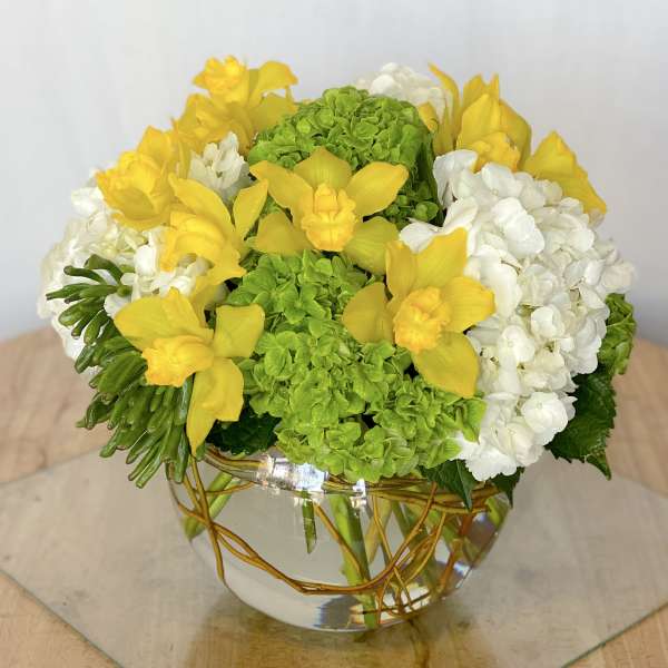 Yellow orchids and white hydrangeas in a glass bowl vase