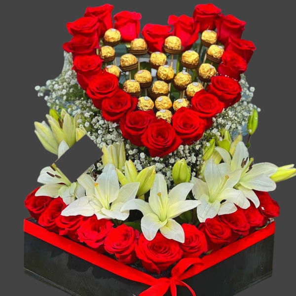 Heart-shaped rose and chocolate arrangement with white lilies in a black box