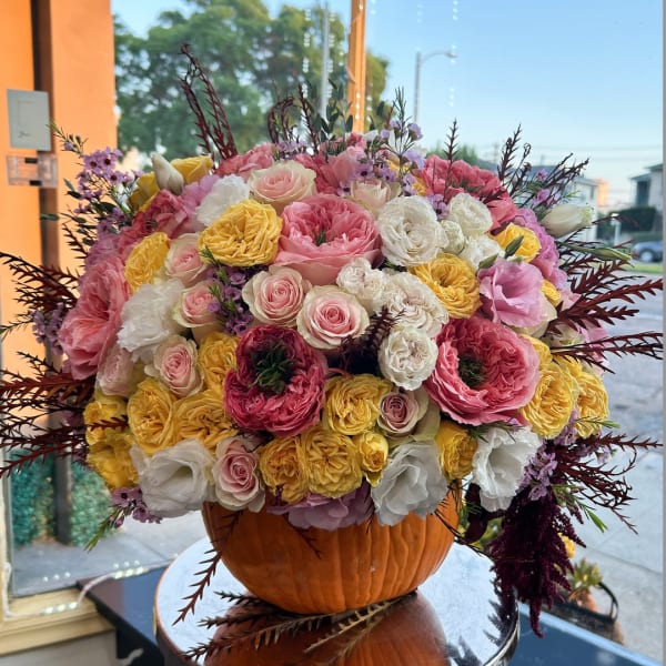 Large bouquet of pink, white, and yellow roses in a pumpkin vase