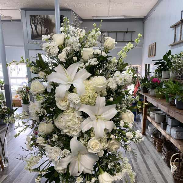 Large white floral standing spray with lilies, roses, and hydrangeas