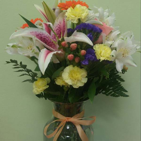 Mixed bouquet in a glass vase with lilies, carnations, and daisies