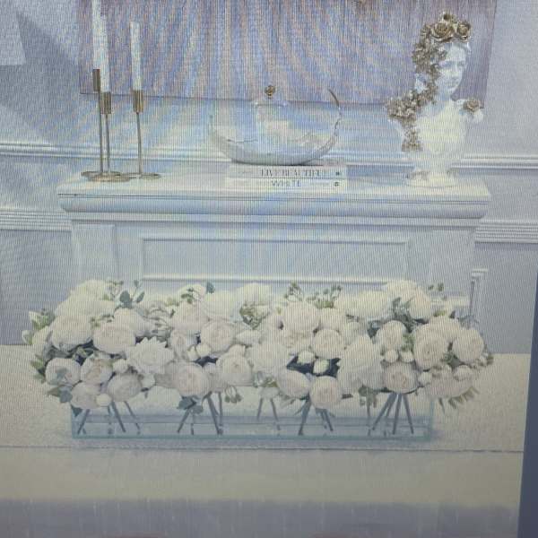 White floral arrangement in a clear rectangular vase on a table