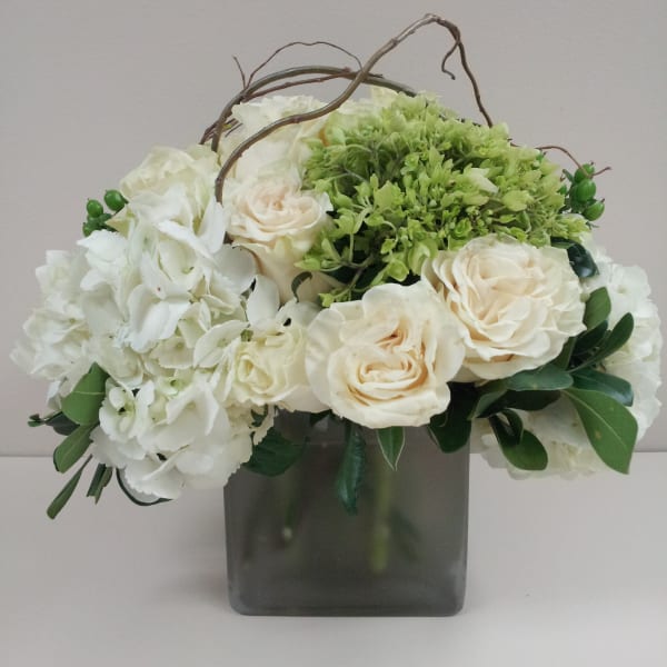 White and cream roses with green hydrangea in a square glass vase