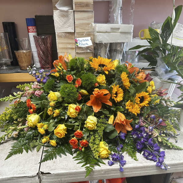 Large mixed floral arrangement with sunflowers, roses, lilies, and purple blooms