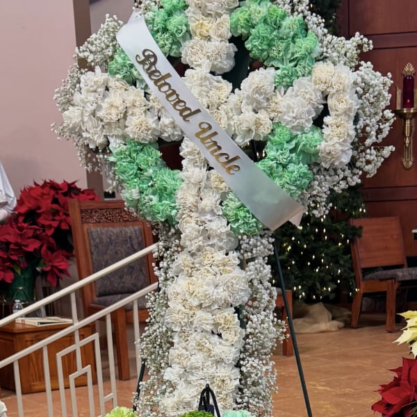 Large white and green floral standing cross with a satin memorial ribbon