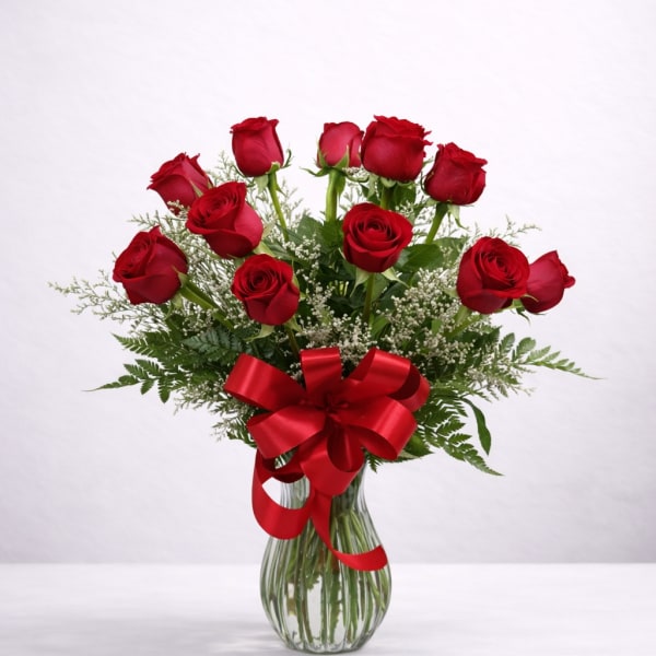 Red roses in a glass vase with a red ribbon bow