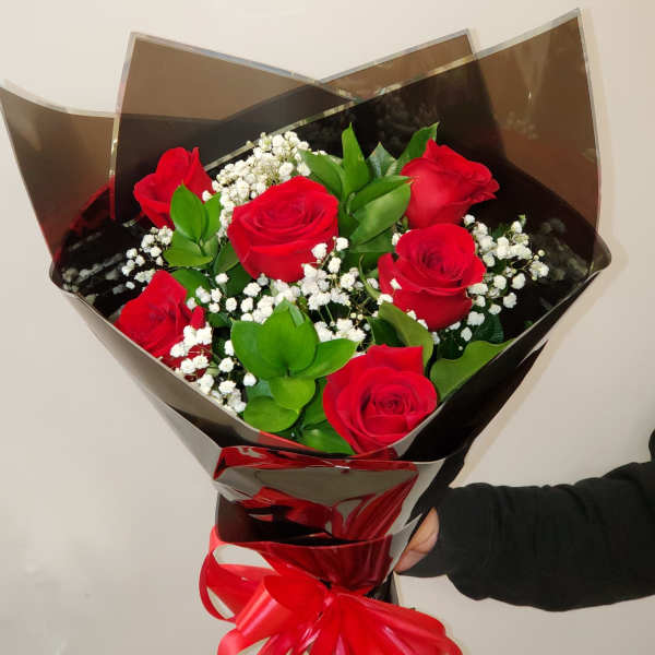 Bouquet of red roses with baby's breath wrapped in dark paper