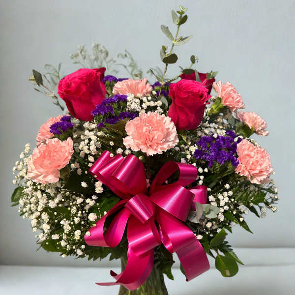 Bouquet of pink roses and carnations with purple filler in a glass vase