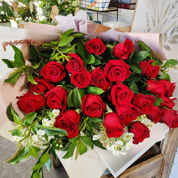 Bouquet of red roses wrapped in pale pink paper