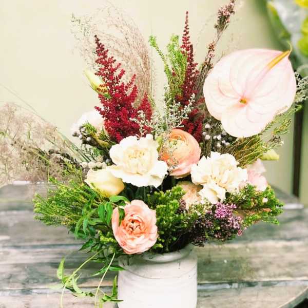 Mixed floral arrangement in a white vase with pale pink and cream blooms