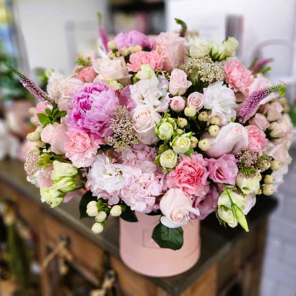 Pink and white mixed flower arrangement in a round box