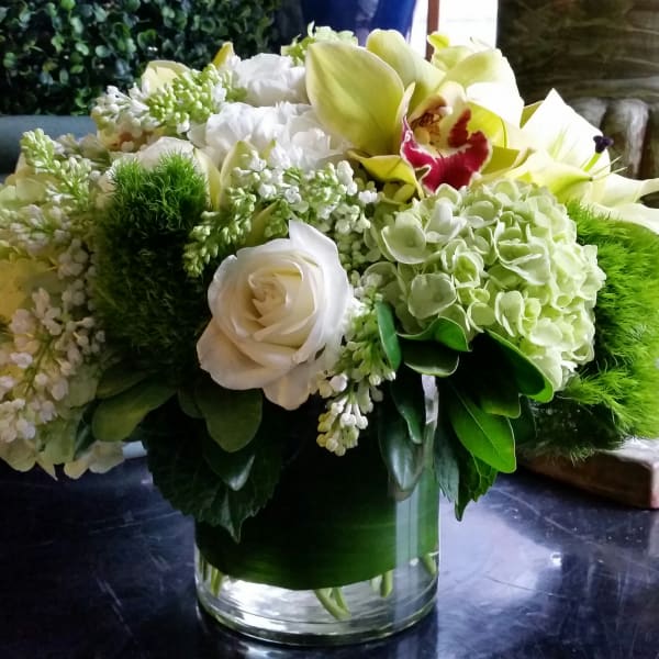 White and green floral arrangement in a clear glass vase