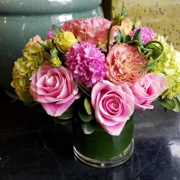 Pink roses and mixed blooms arranged in a glass vase