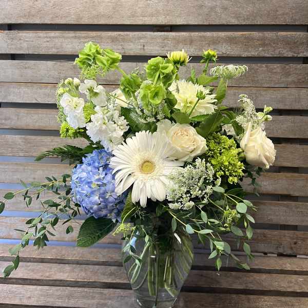 Mixed white and blue flowers arranged in a clear glass vase