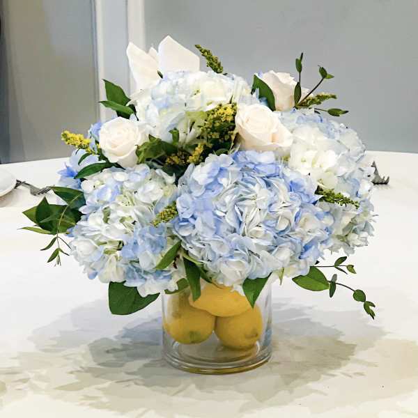 Blue and white flower arrangement in a glass vase with lemons
